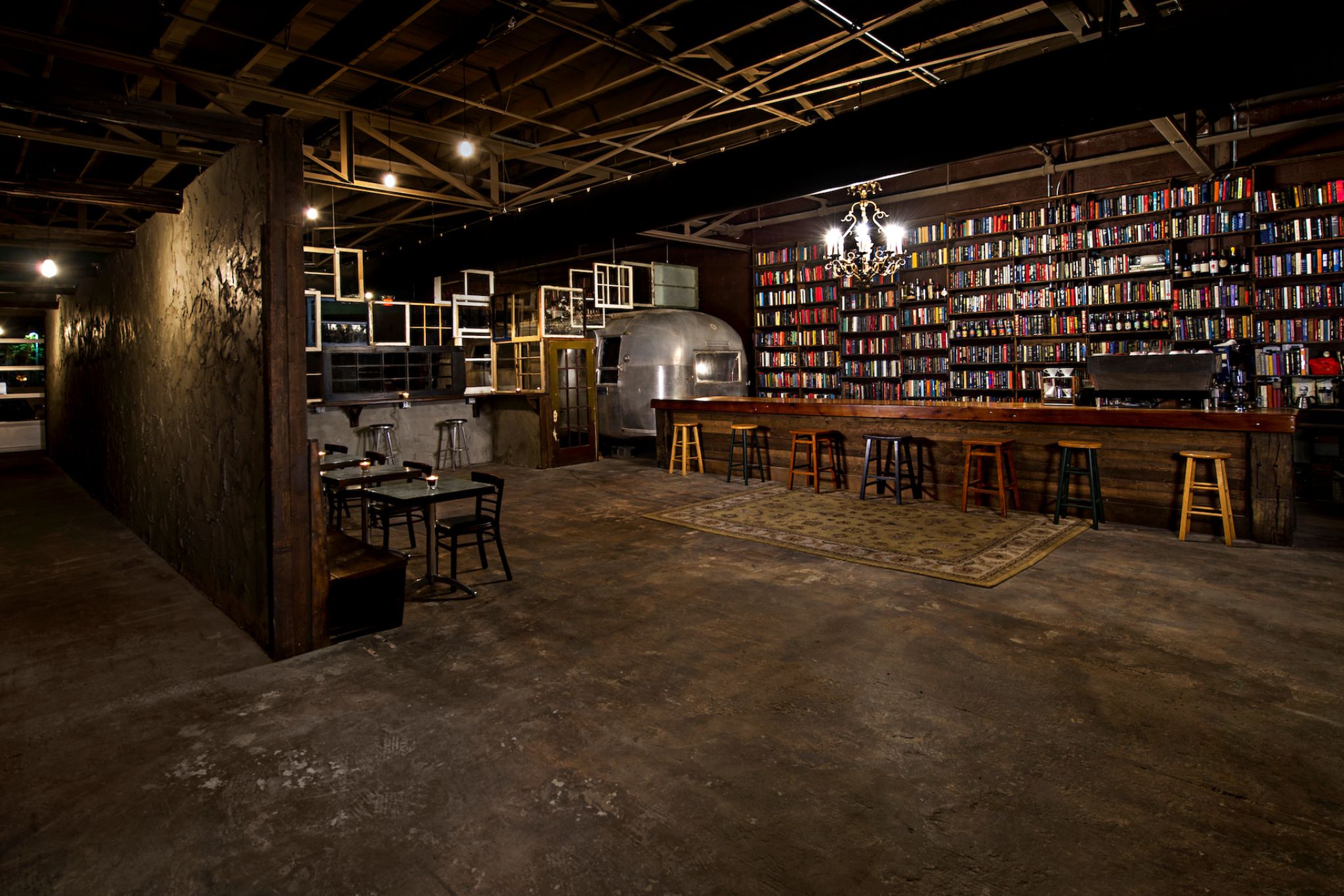 IU C&I Studios Page Room with a wooden chairs with tables, barstools at a Nextdoor Florida bar rental place. There is an old metallic RV in the background.