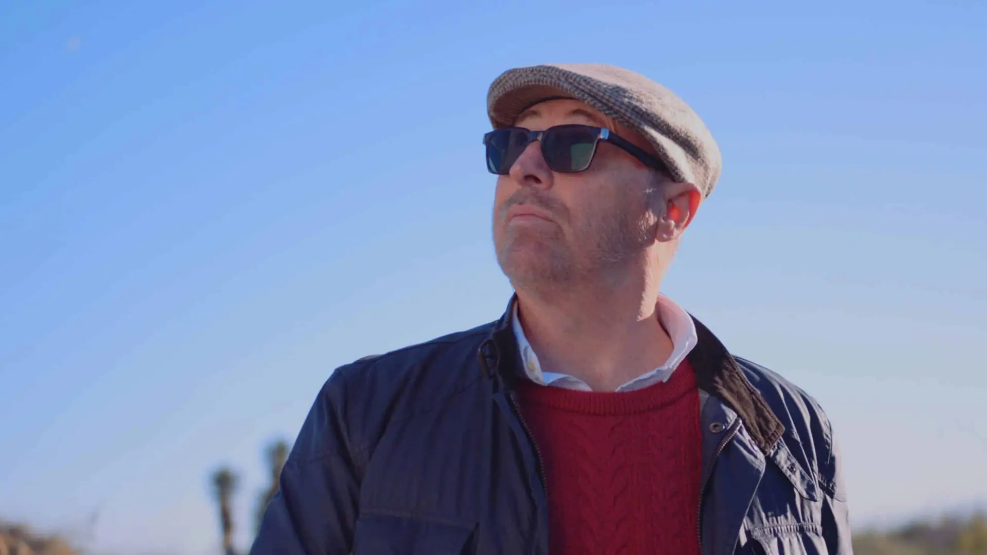 cis-portfolio-beltempo3 Man wearing brown cap, navy blue jacket and red sweater looking away from camera