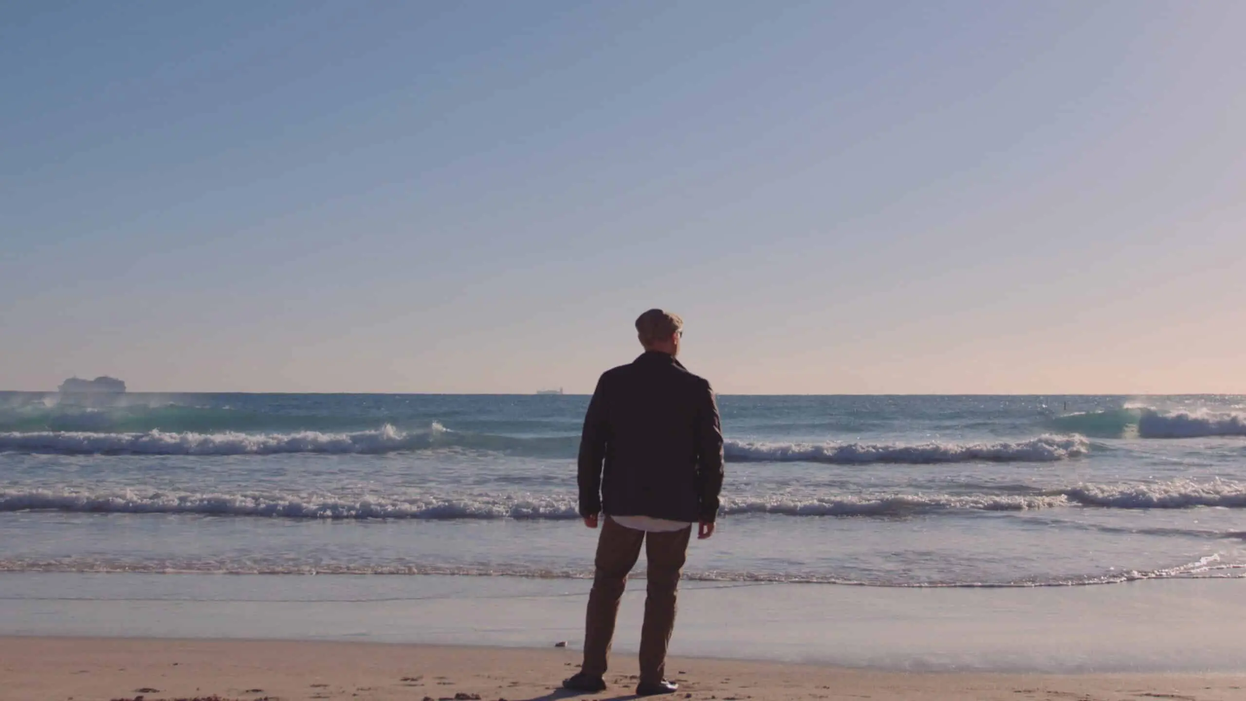 fvp-portfolio-beltempo5 View from behind of man wearing brown cap and navy blue jacket looking over the ocean