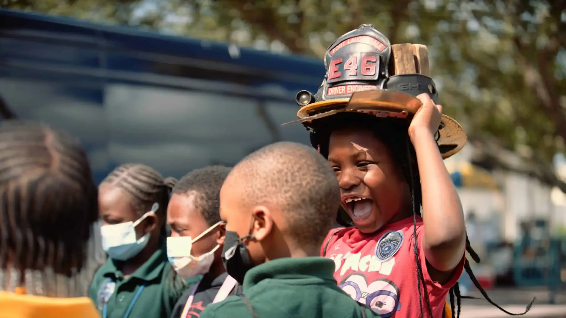 Ranger Technical Resources 32 African American boy wearing a fire helmet laughing with other boys and girls nearby