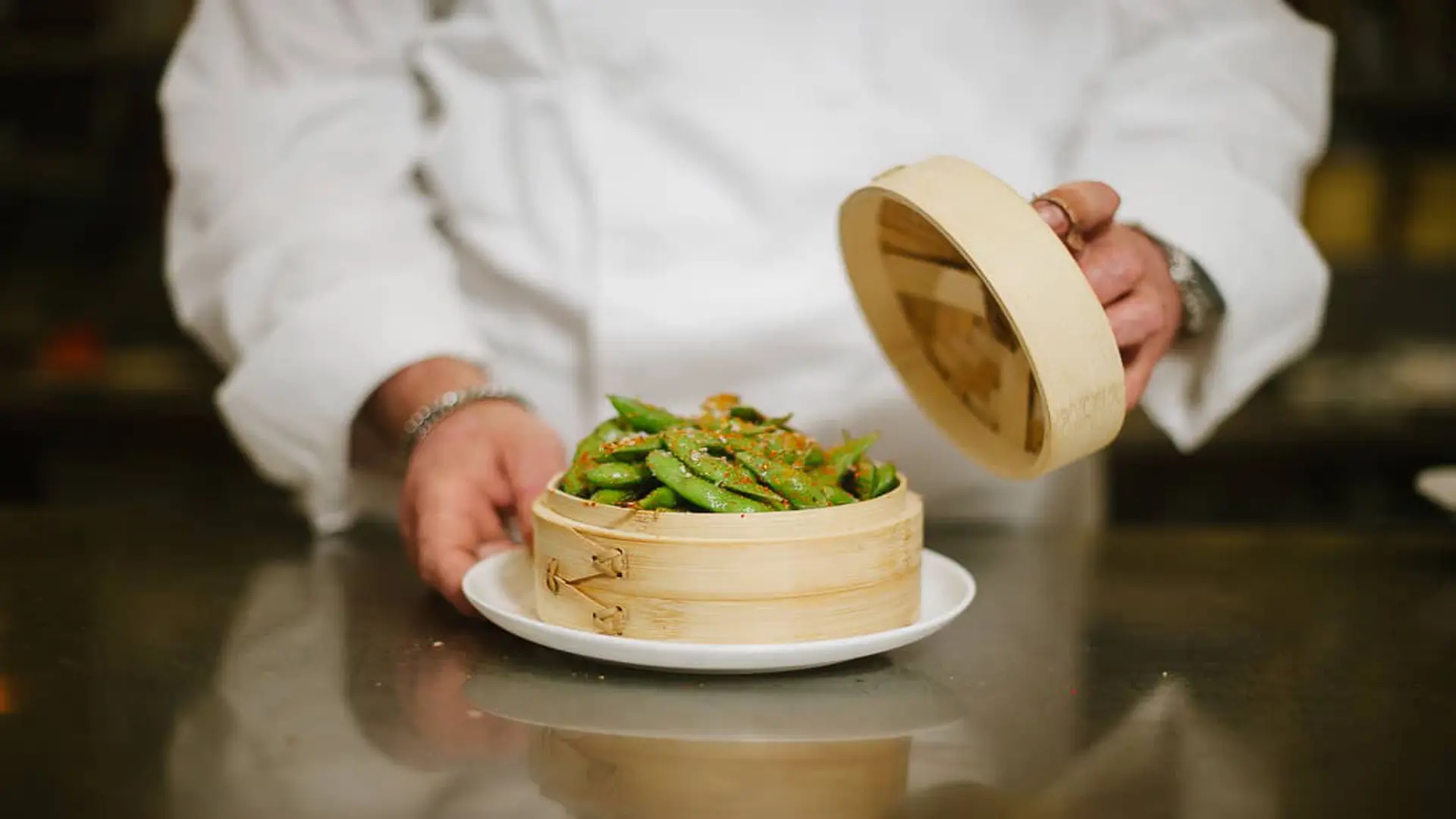 Gold Coast Magazine 69 Closeup of a dish of snap peas in a bamboo container presented by a chef