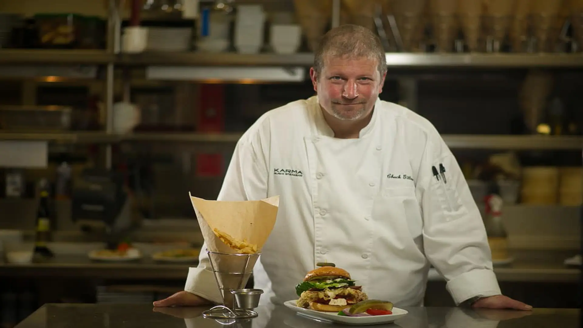 Gold Coast Magazine 68 Chef presenting french fries and burger with pickle and tomato