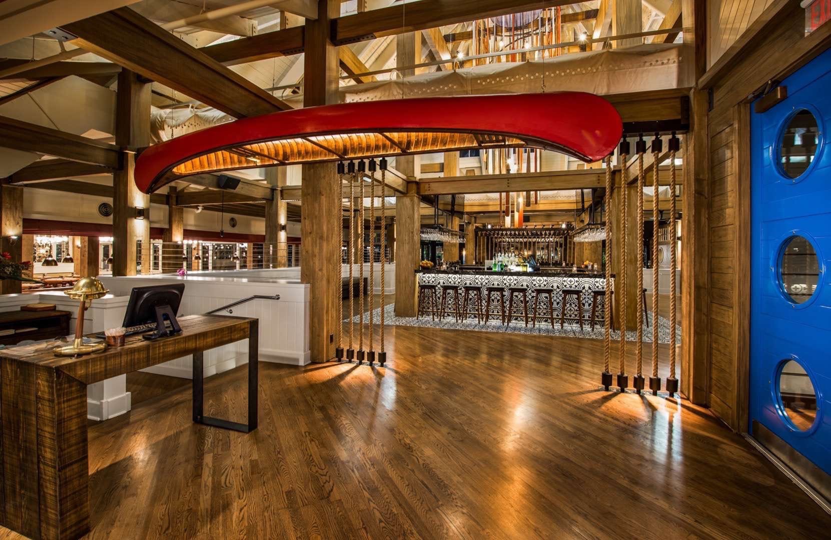 IU C&I Studios Portfolio The Restaurant People Inside view of the Boatyard restaurant with a canoe hanging from rafters as well as check in and out table and bar
