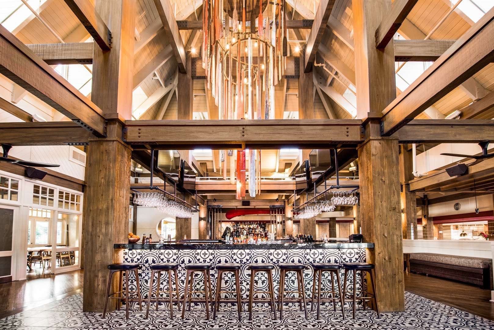 CI Studios Portfolio The Restaurant People Chandelier with oars hanging from the ceiling over a bar with many barstools and tiled