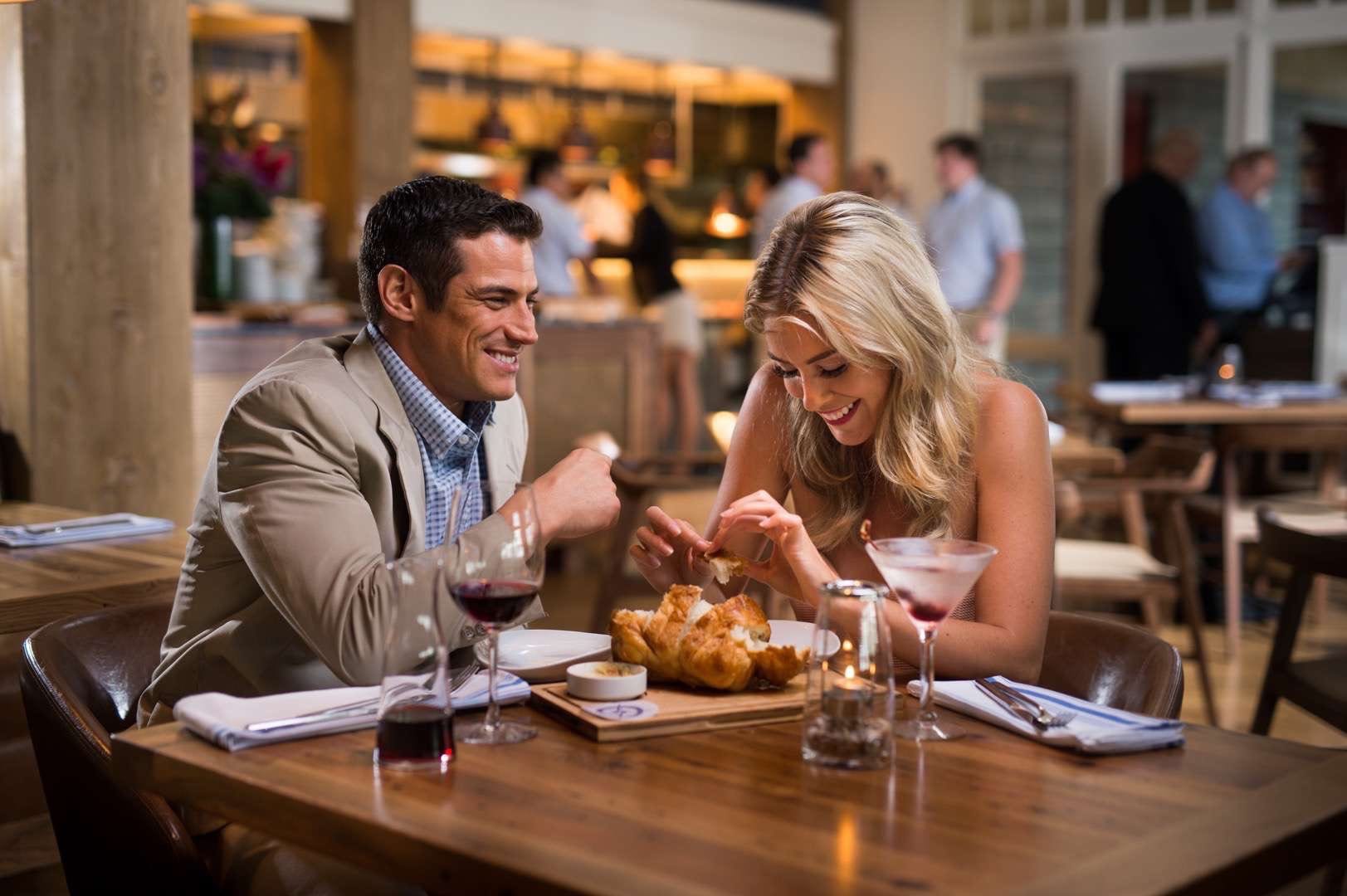 CI Studios Portfolio The Restaurant People Young man and woman having bread at the dinner table smiling