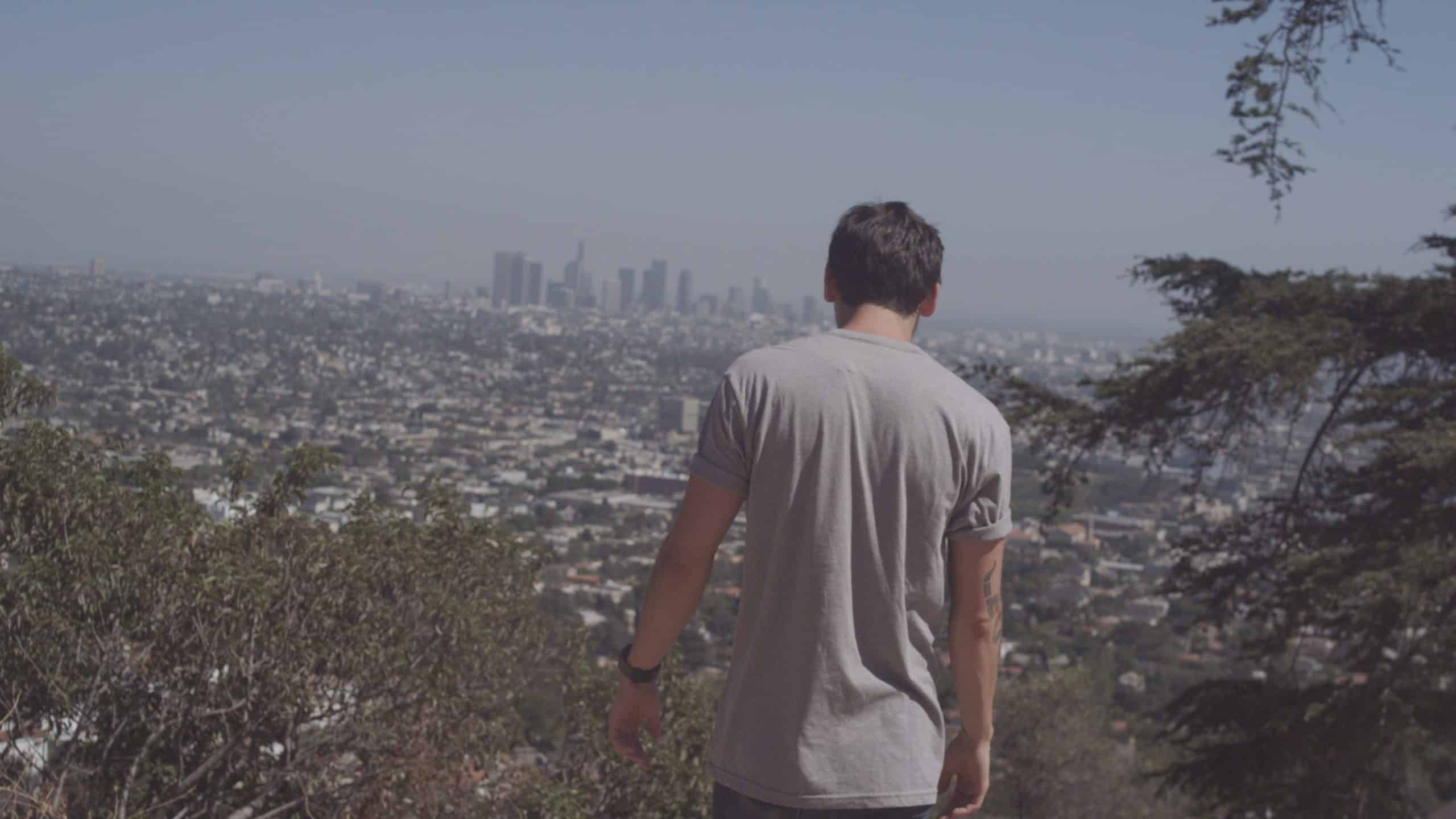 Uncreative Stories Joe Perri Profile View from behind of man with short brown hair wearing a gray t shirt looking out over a city