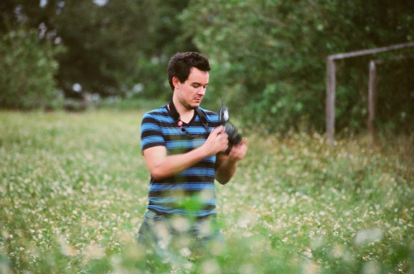 Uncreative Blog Man in a blue and black shirt holding a camera in a field