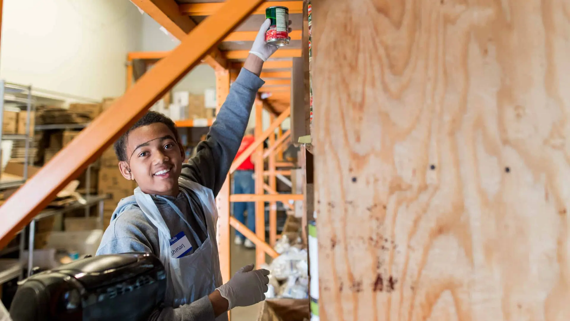 United Way 227 Side profile of a boy who works at the facility putting a can on the shelf smiling