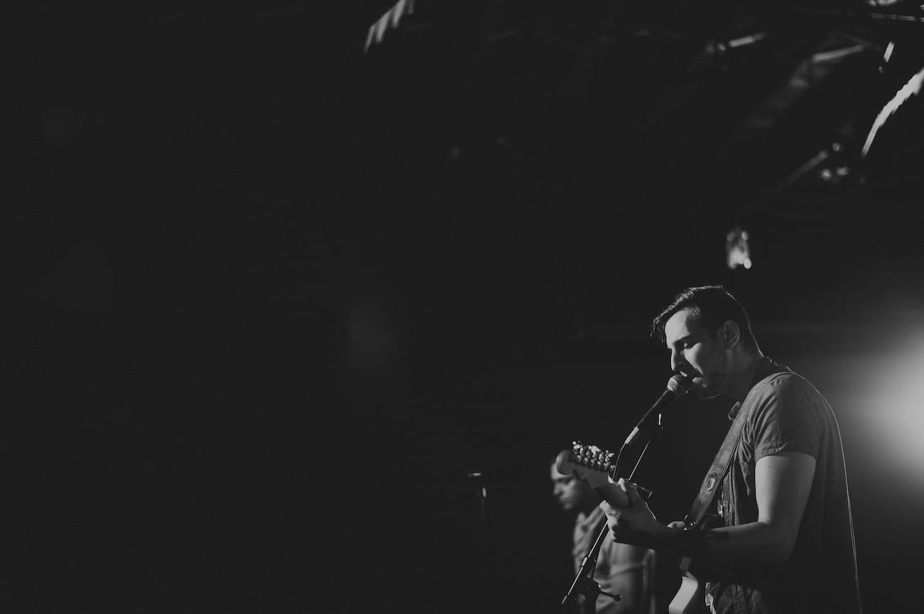 Black and white of a male guitarist with another male performer.