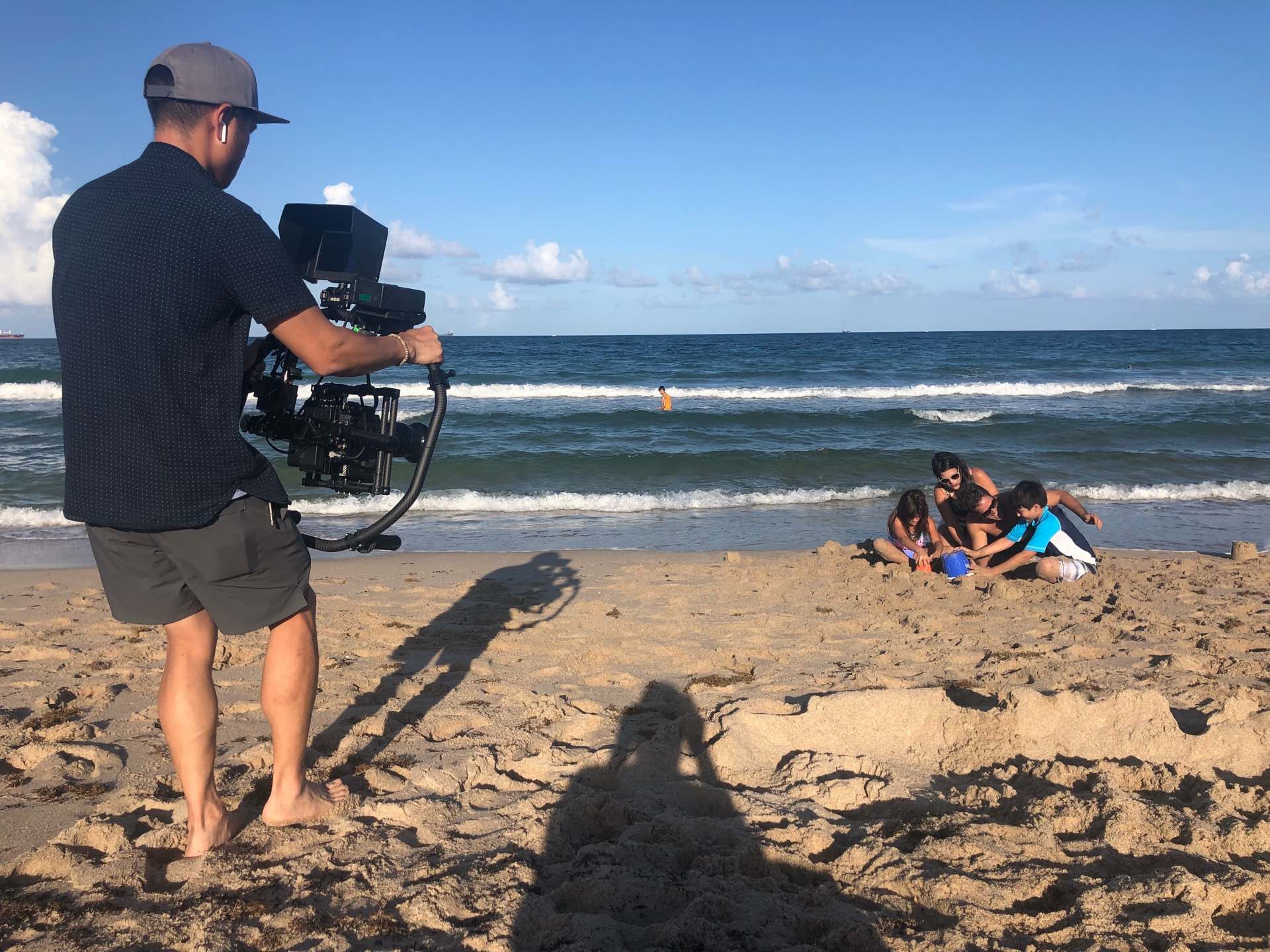 Tavistock Development Company Behind the scenes Video cameraman filming family with two kids playing in the sand at the beach