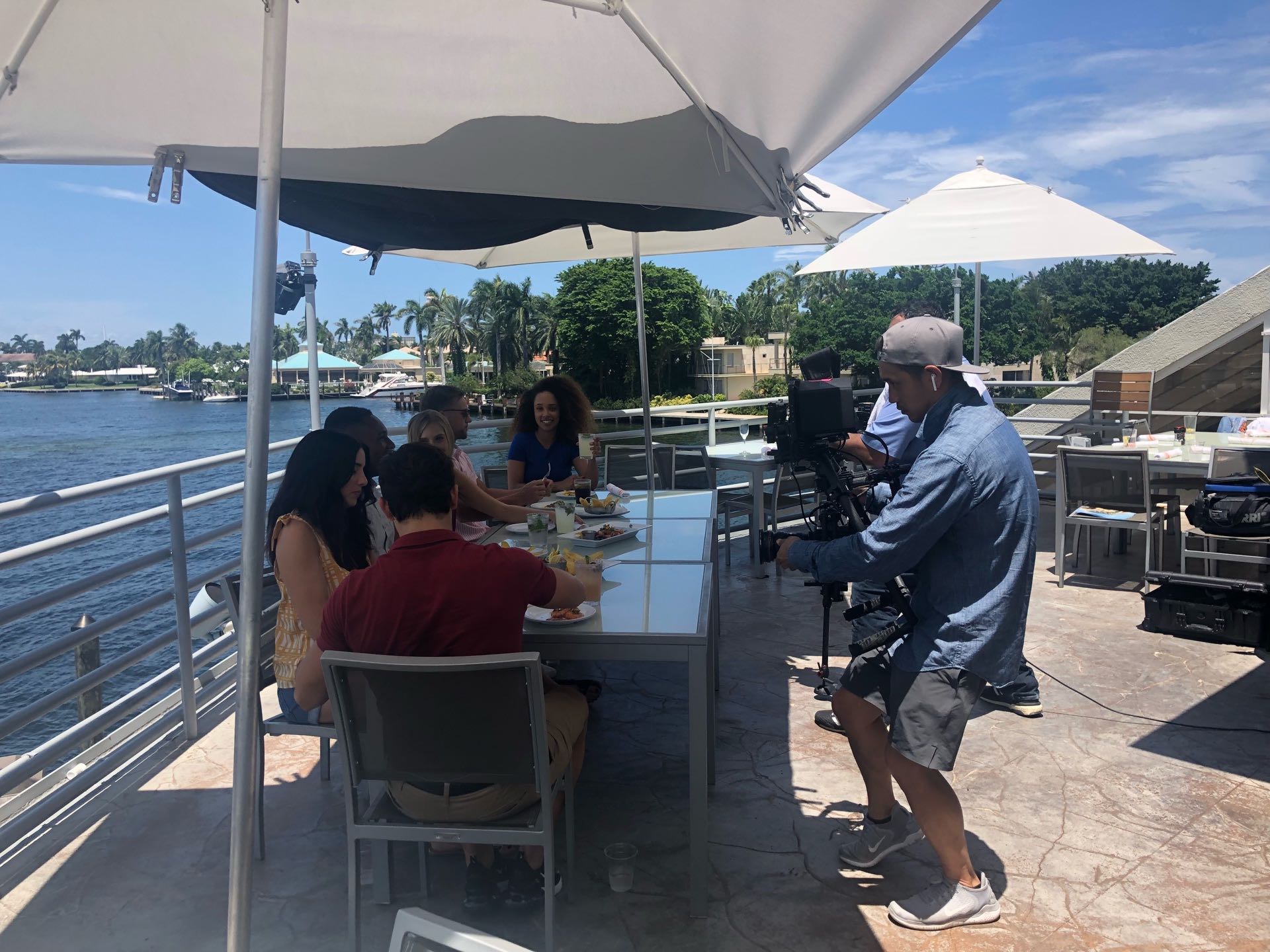 Behind the scenes Video cameraman filming a family enjoying food on a restaurant patio