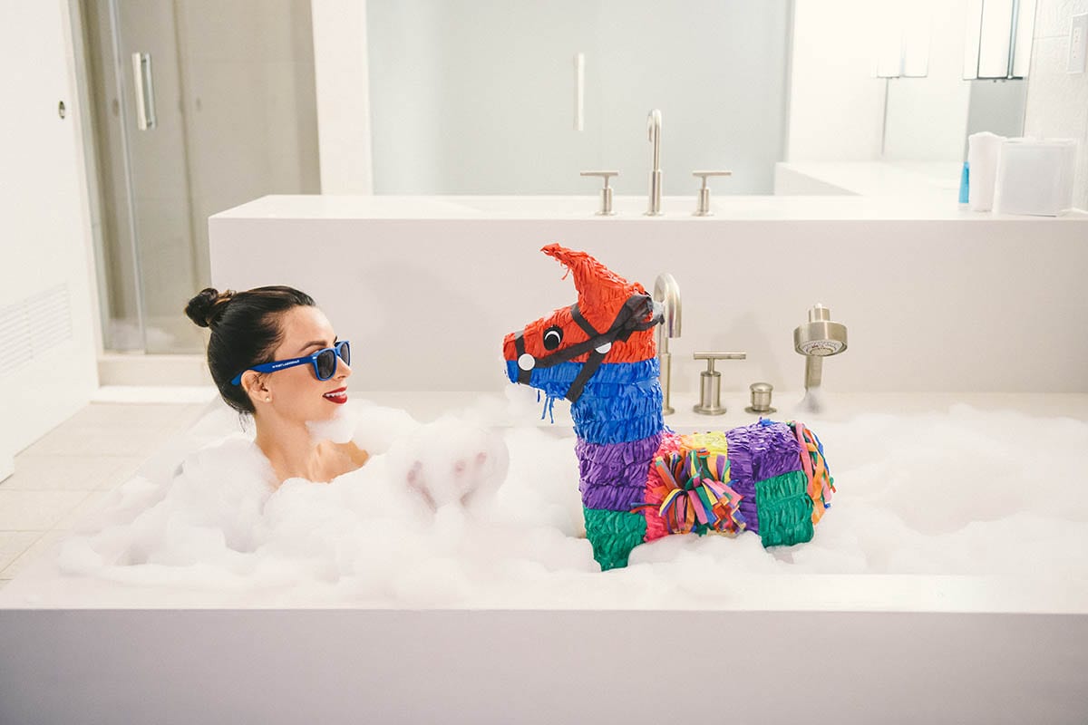 Social media marketing C&I studios bath Woman taking a bubble bath with a multicolored pinata of a horse nearby