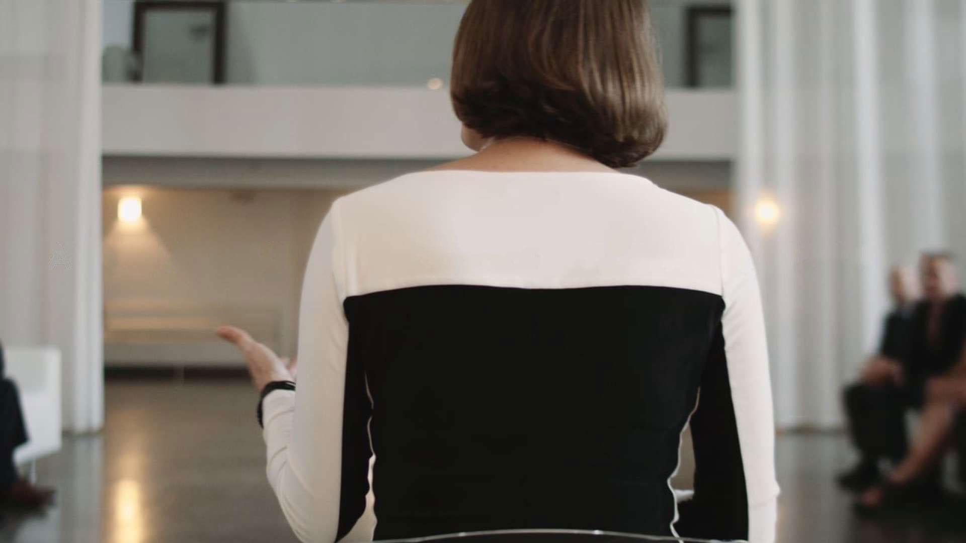 Woman in black and white outfit with back to camera talking to people