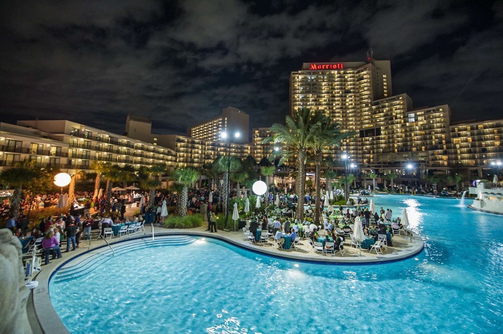 Nighttime view of the Marriott at Orlando World Center's pool surrounded by patio filled with people.