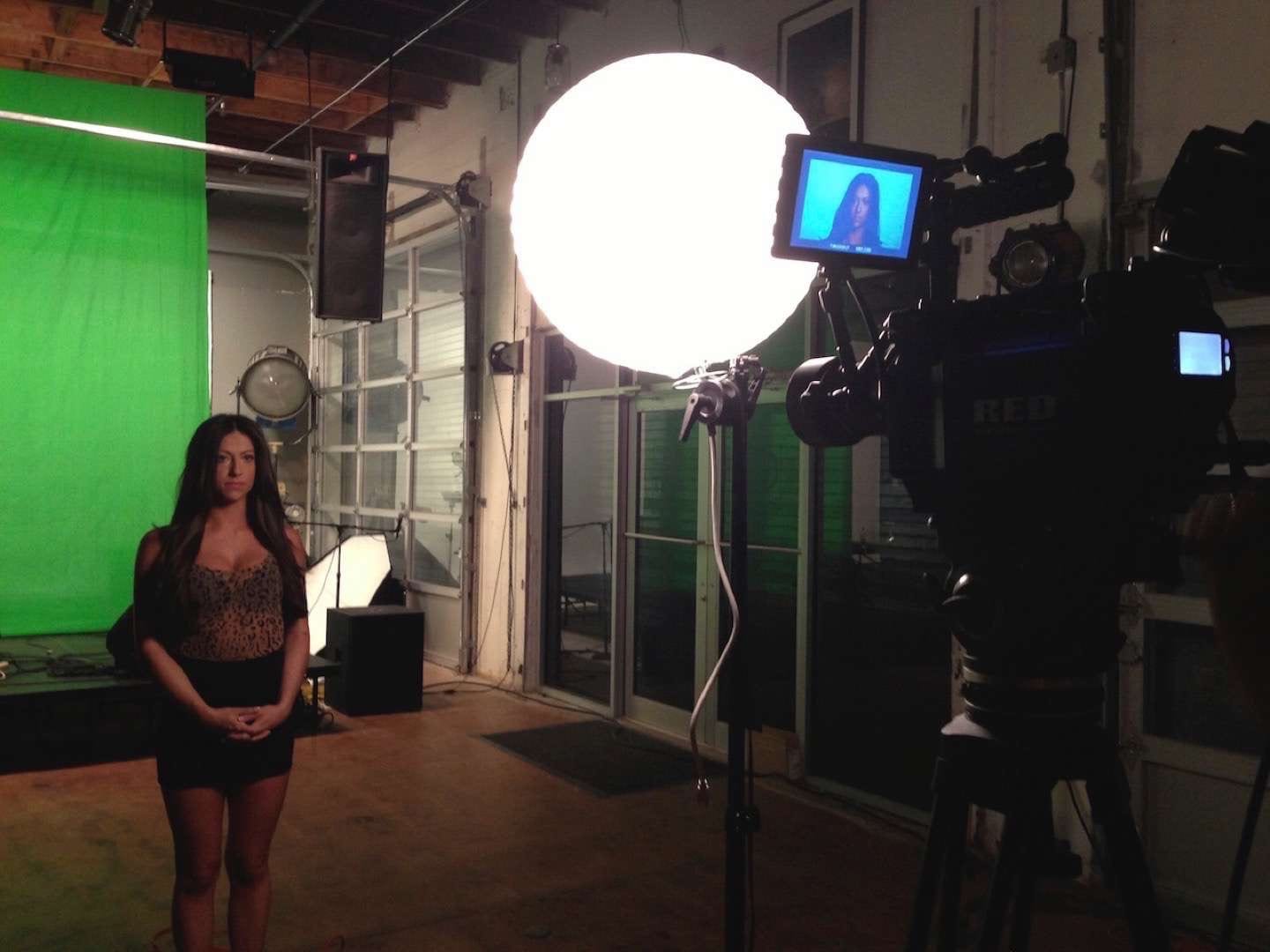 Woman with long brown hair against a green screen being filmed