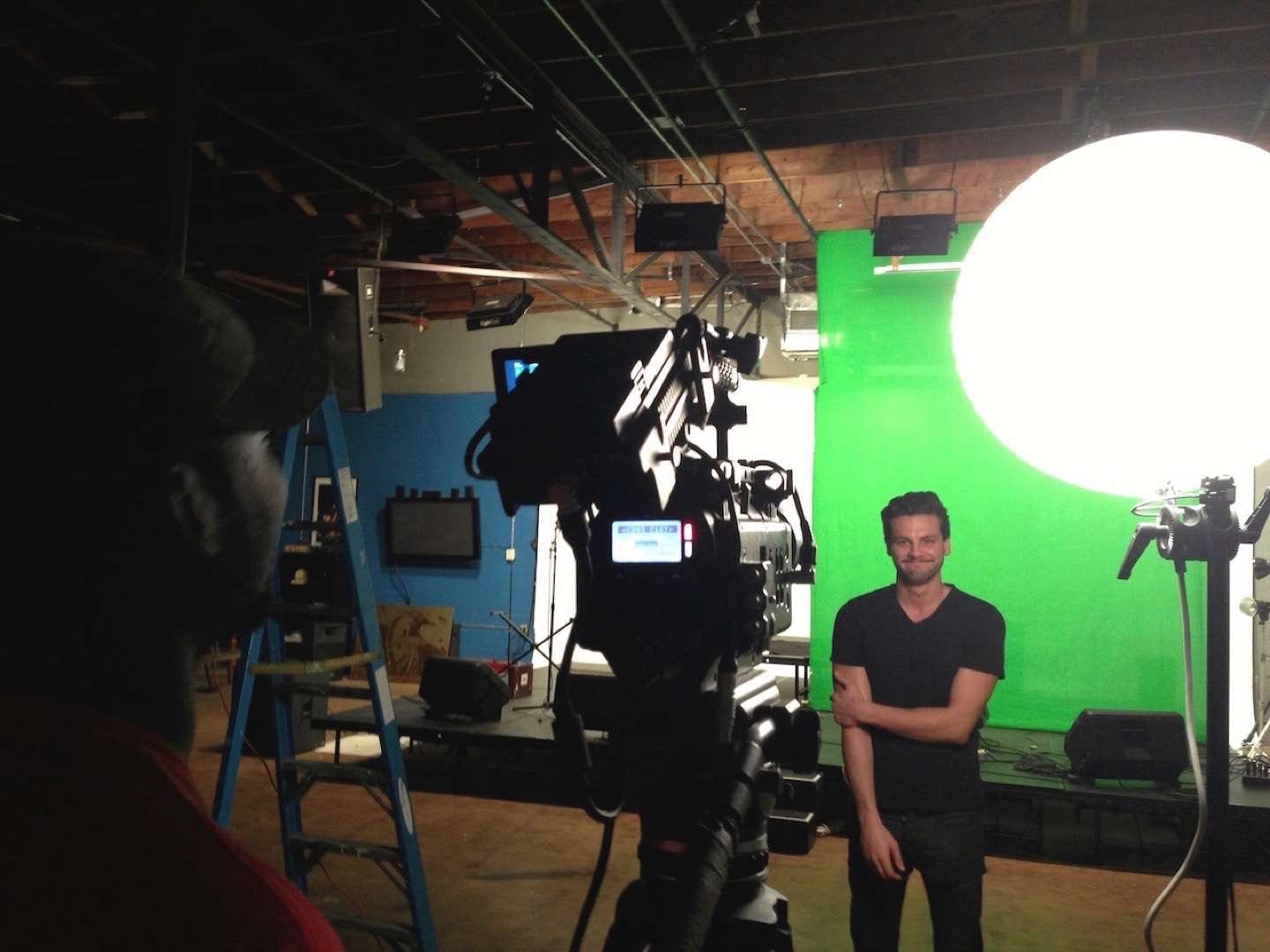 Man against a green backdrop being filmed