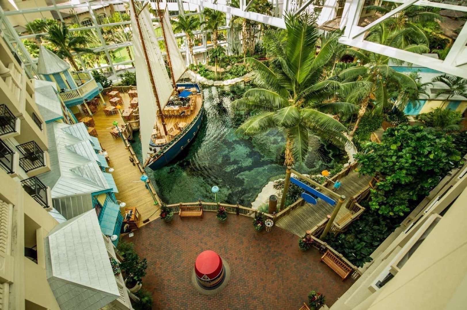 Overhead view of Interior showing a marine themed area with a small ship, walkways, marker, palm trees and trees.