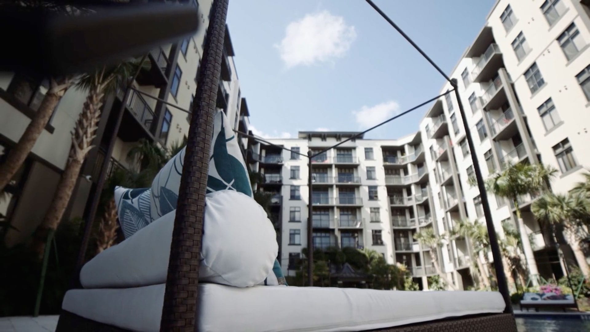 Bed with designer pillows in an outdoor courtyard of a hotel with palm trees