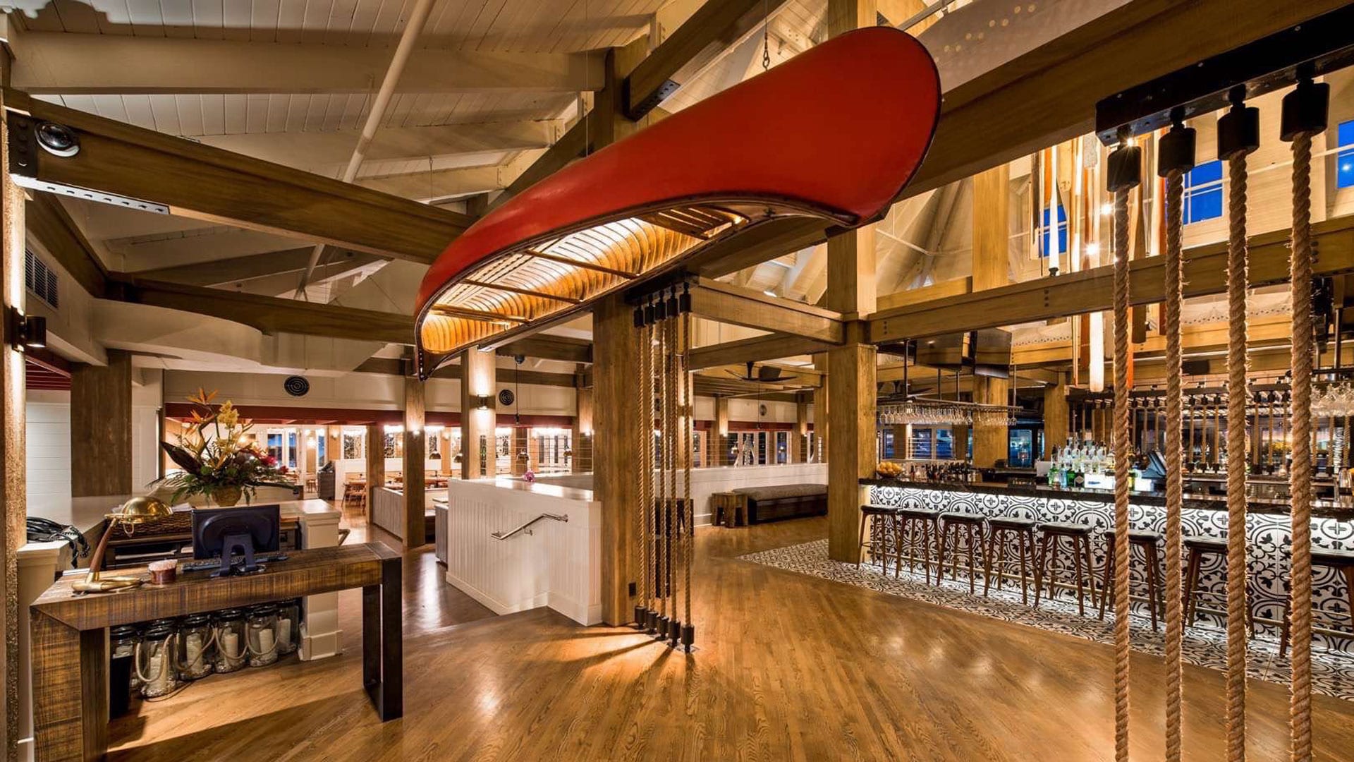 View of the inside of a restaurant and bar with a canoe hanging upside down from the ceiling.