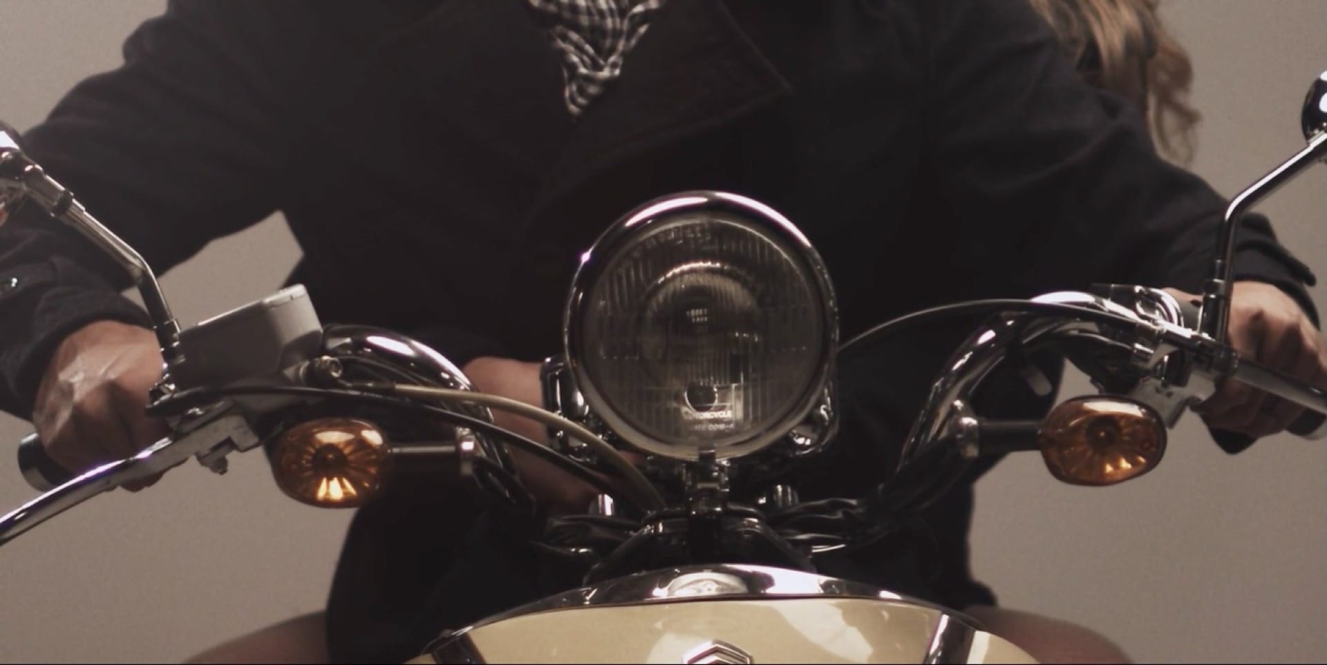 Closeup scene of front of old motorcycle from Classic: Sara Bost + Zach Miller