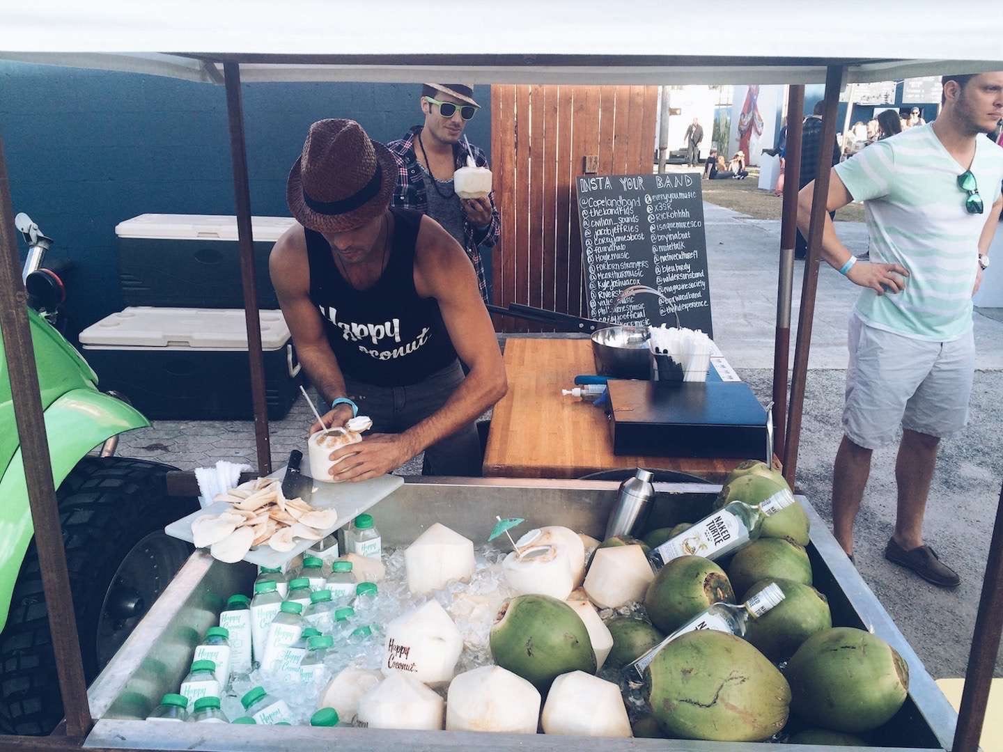 Man preparing a coconut drink for customer from a cart at For the Love Music Festival