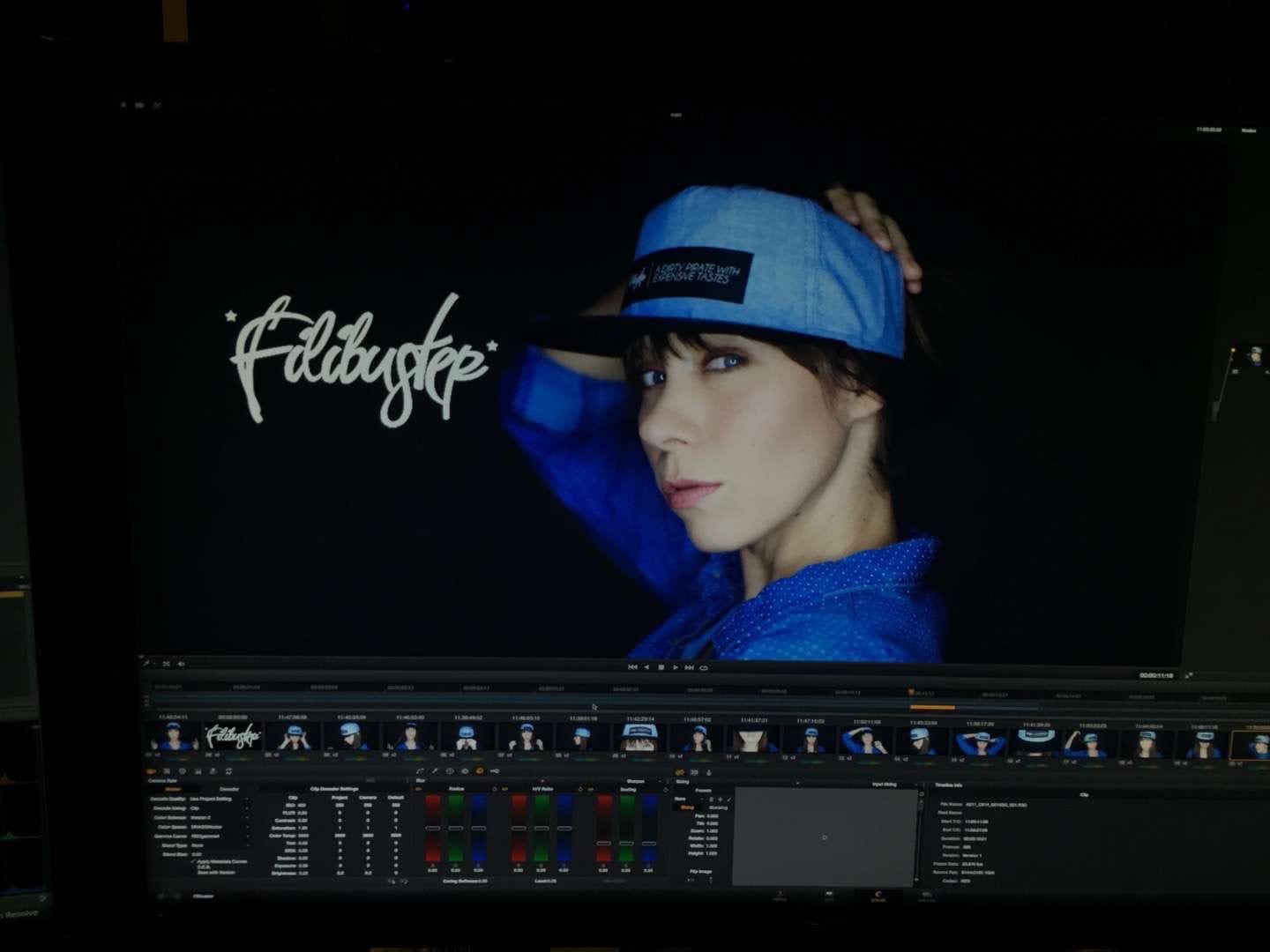 IU C&I Studio Portfolio Filibuster Apparel Video display of white logo with woman with long brown hair in a blue shirt wearing a light blue hat with black rim