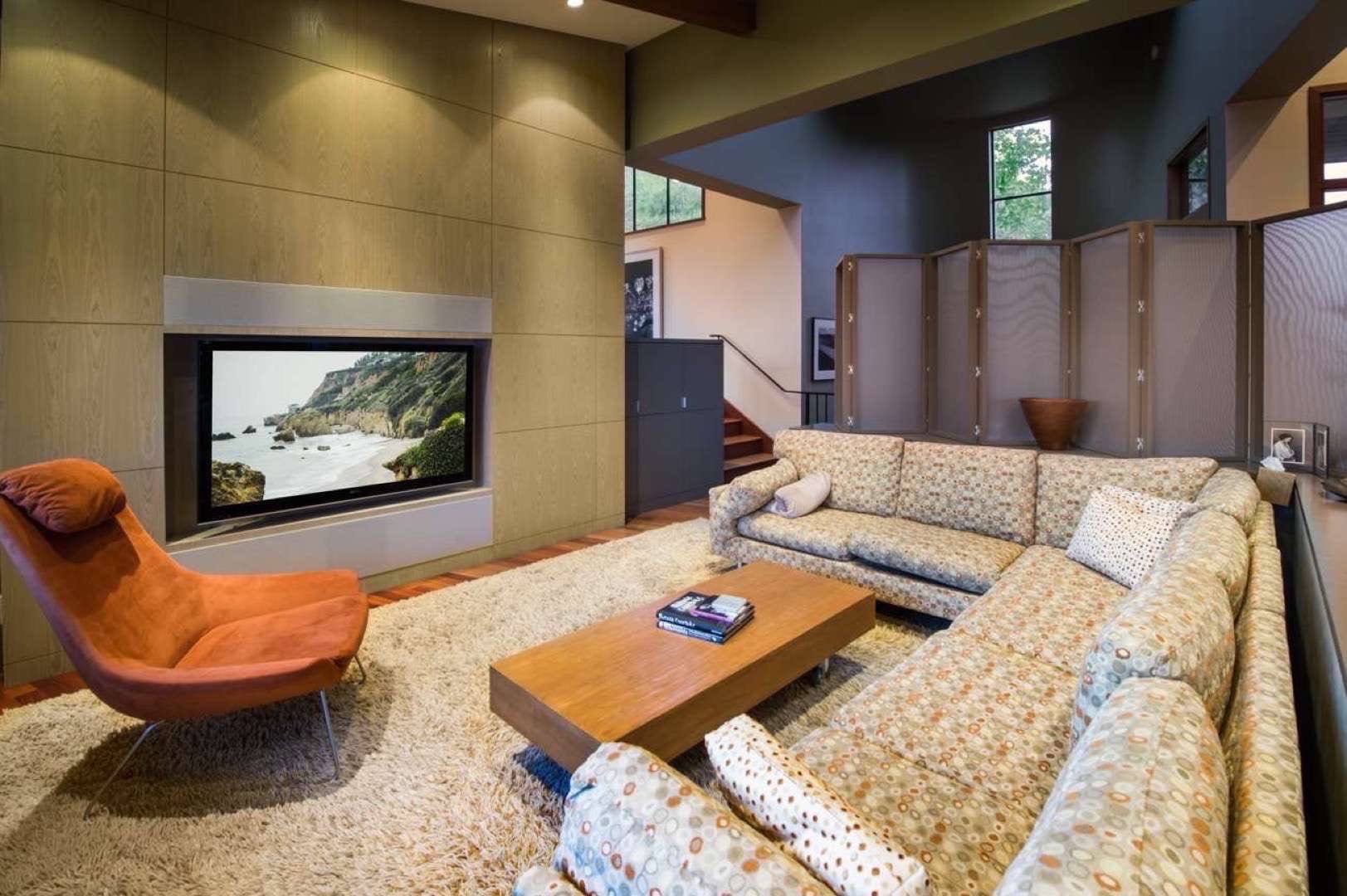 Truly Great Homes View of a living room area with a large screen TV and wrap around couch. There is also a privacy screen in the background.