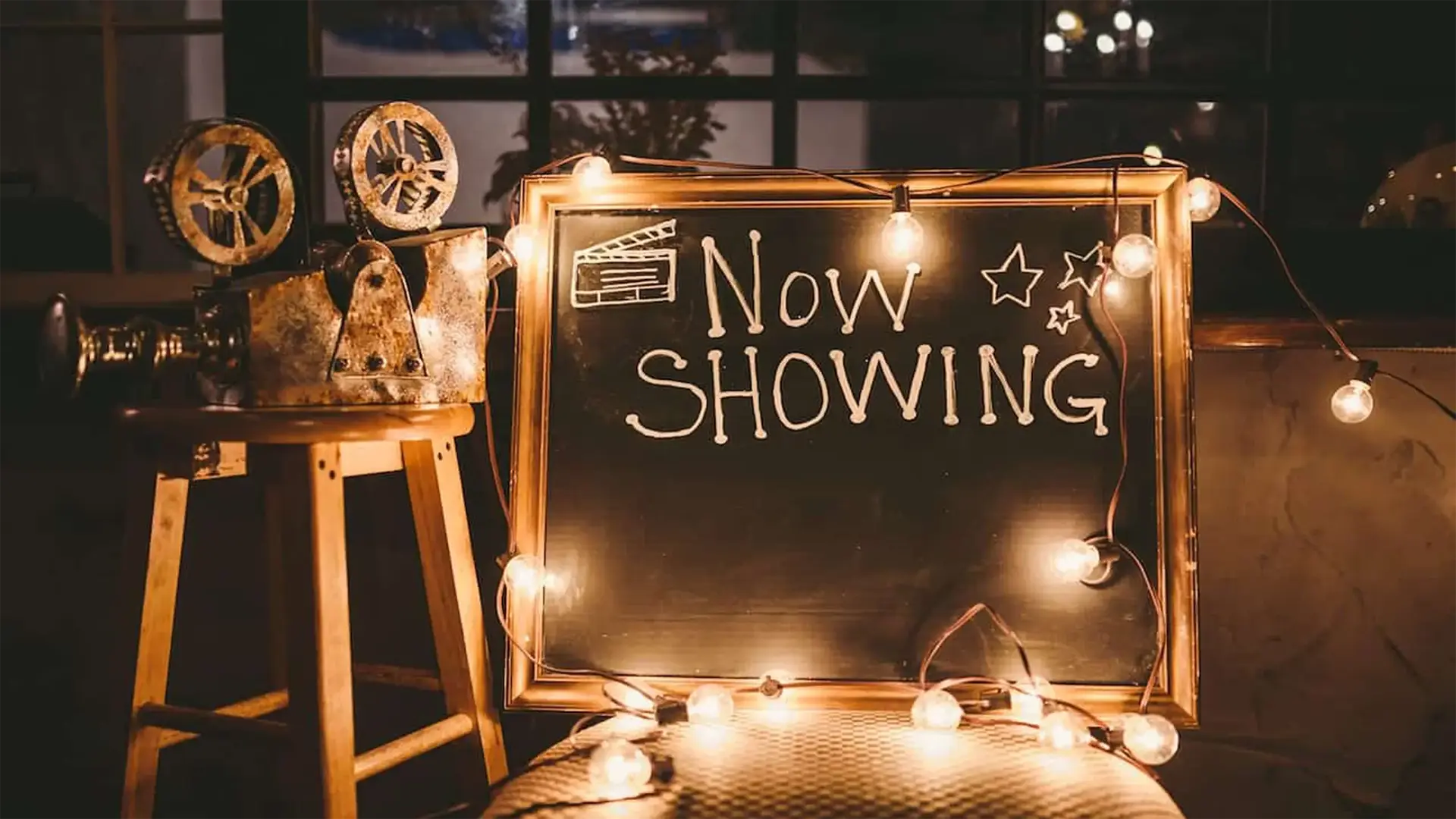 post-were-hosting-south-florida-event-planning3 Mockup of event planning with purpose with makeshift video projector on a wooden stool with a chalkboard sign saying Now Showing with bulb lights,