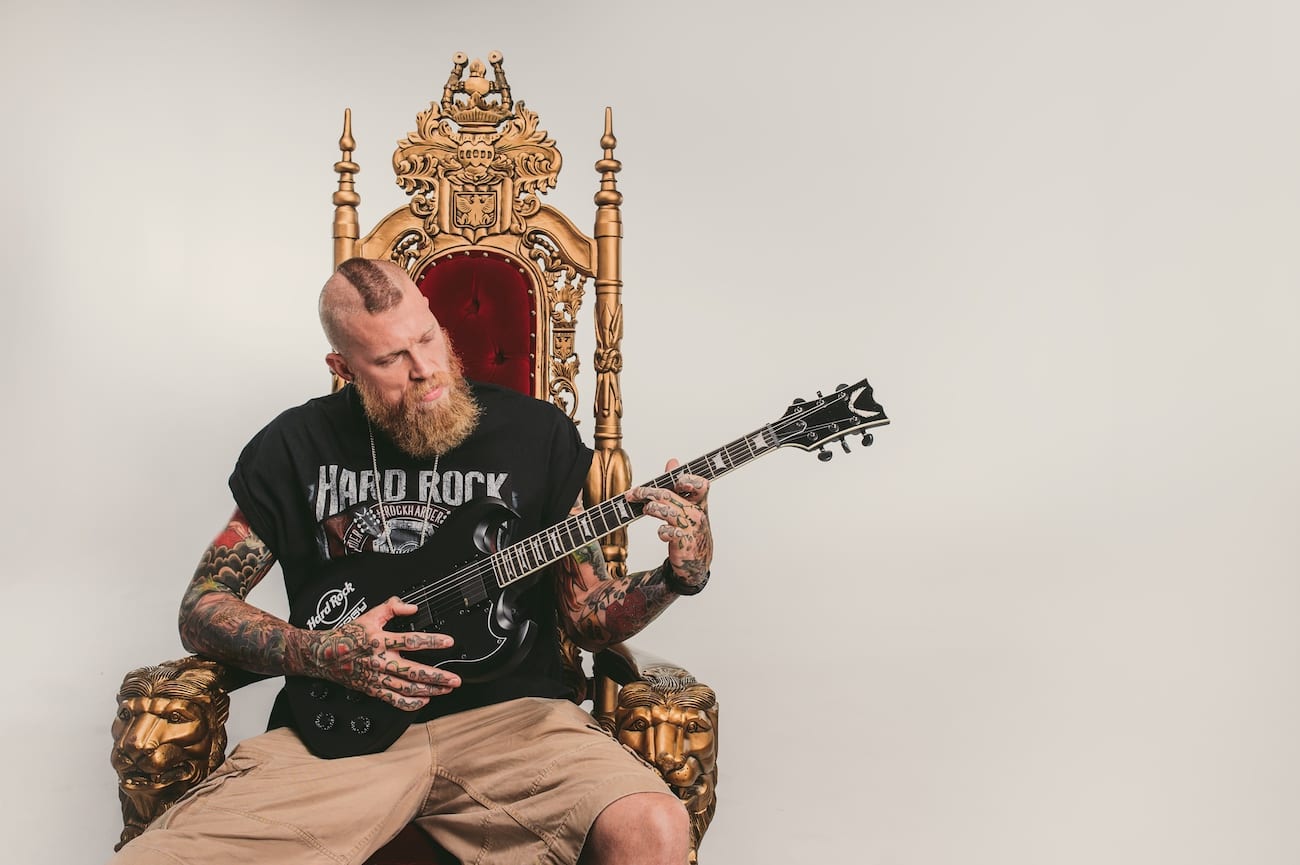 Facebook Story Ads Tattooed man with mohawk for Hard Rock Energy drinks posing for camera on a throne playing a guitar