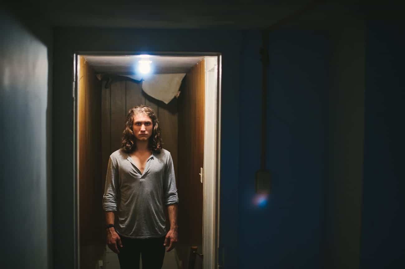 Government Sanctioned Social Media Censorship Man with long brown hair posing for camera standing in a narrow hallway