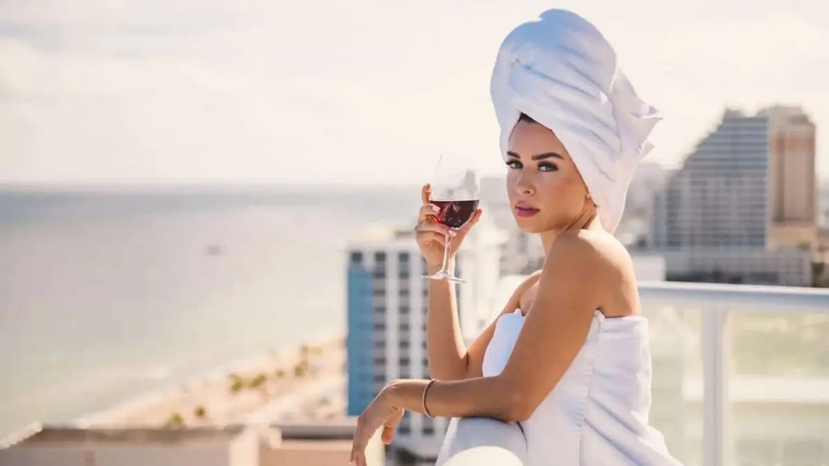 W Fort Lauderdale 11 Woman wearing white towels on body and head enjoying a glass of wine leaning on a balcony railing posing for the camera