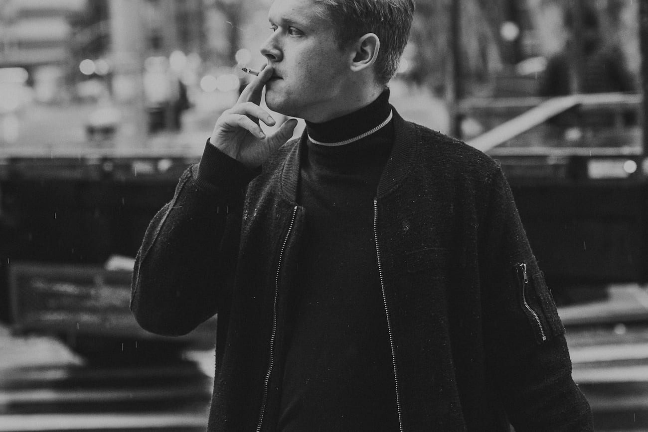 Black and white of man with short hair smoking a cigarette