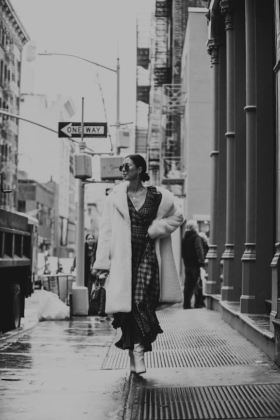 NYFW Off-White Clothing Black and white of woman walking down a city street wearing plush coat