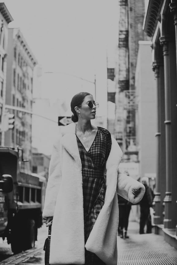 NYFW Off-White Clothing Black and white closeup of woman walking down a city street wearing plush coat