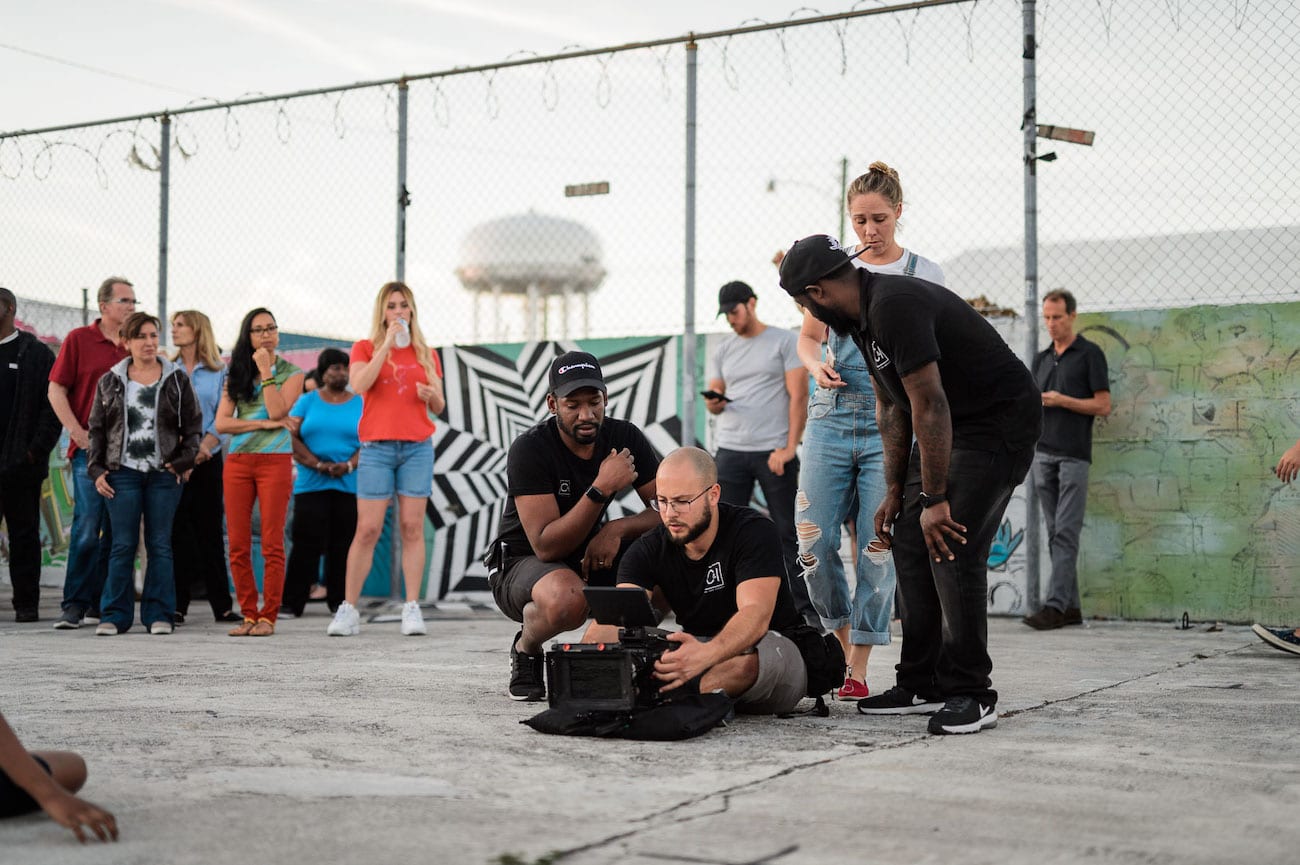 OneUnited BTS 26 Advertising Agency in Fort Lauderdale Protester being filmed by video cameraman sitting on the ground with group of people behind him