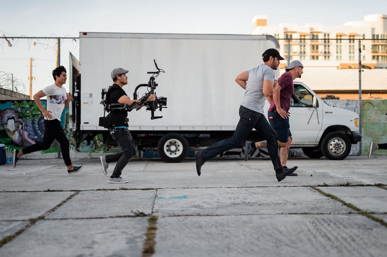 OneUnited BTS 5 Advertising Agency in Fort Lauderdale Group of people running in front of a box car with a video cameraman amongst them.