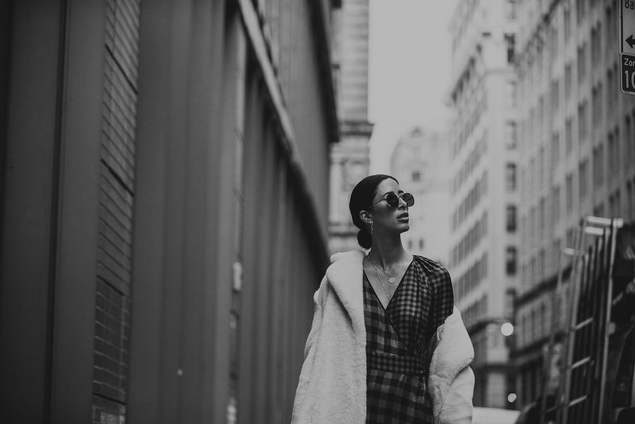 Black and white closeup of woman walking down a city street wearing plush coat