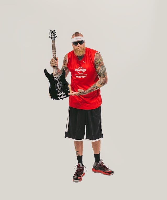 Hard Rock Energy Drink Marketing by C&I Studios Bearded tattooed man wearing a red Hard Rock Energy jersey and black shorts holding a guitar