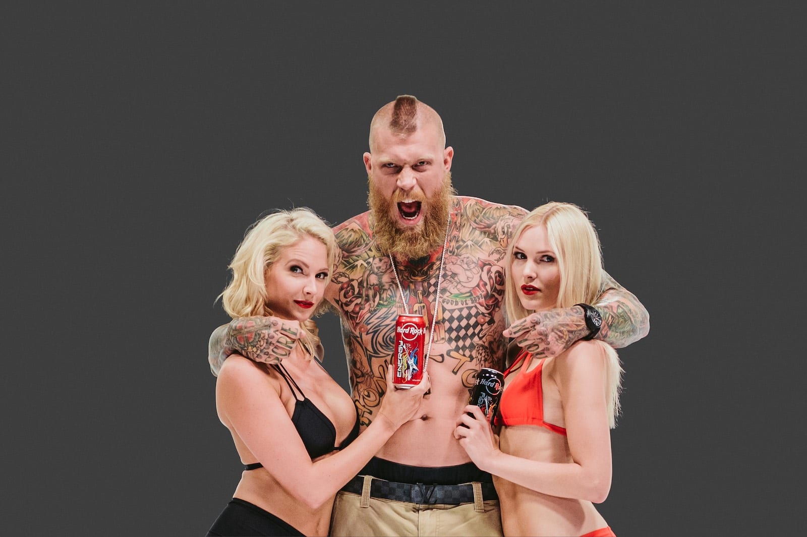 Hard Rock Energy, Marketing by C&I Studios Bearded tattooed man holding two women holding Hard Rock Energy drinks next to him posing for camera