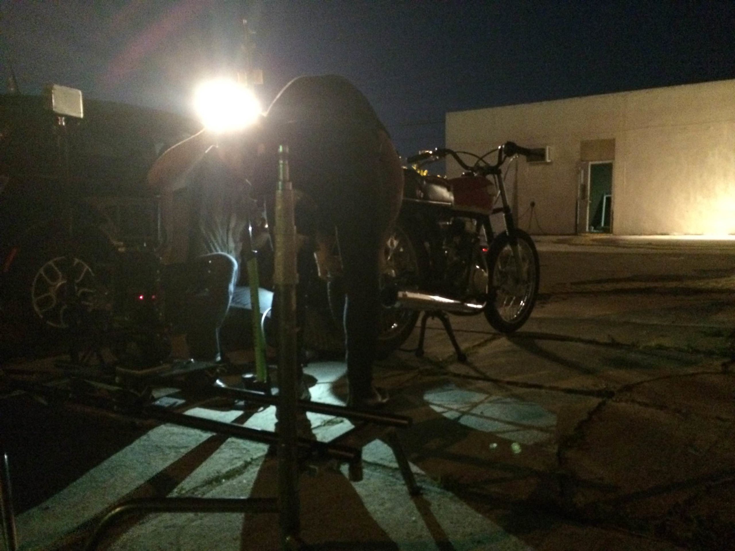 Hard Rock Energy BTS Crew members working near motorcycle in the dark with a light