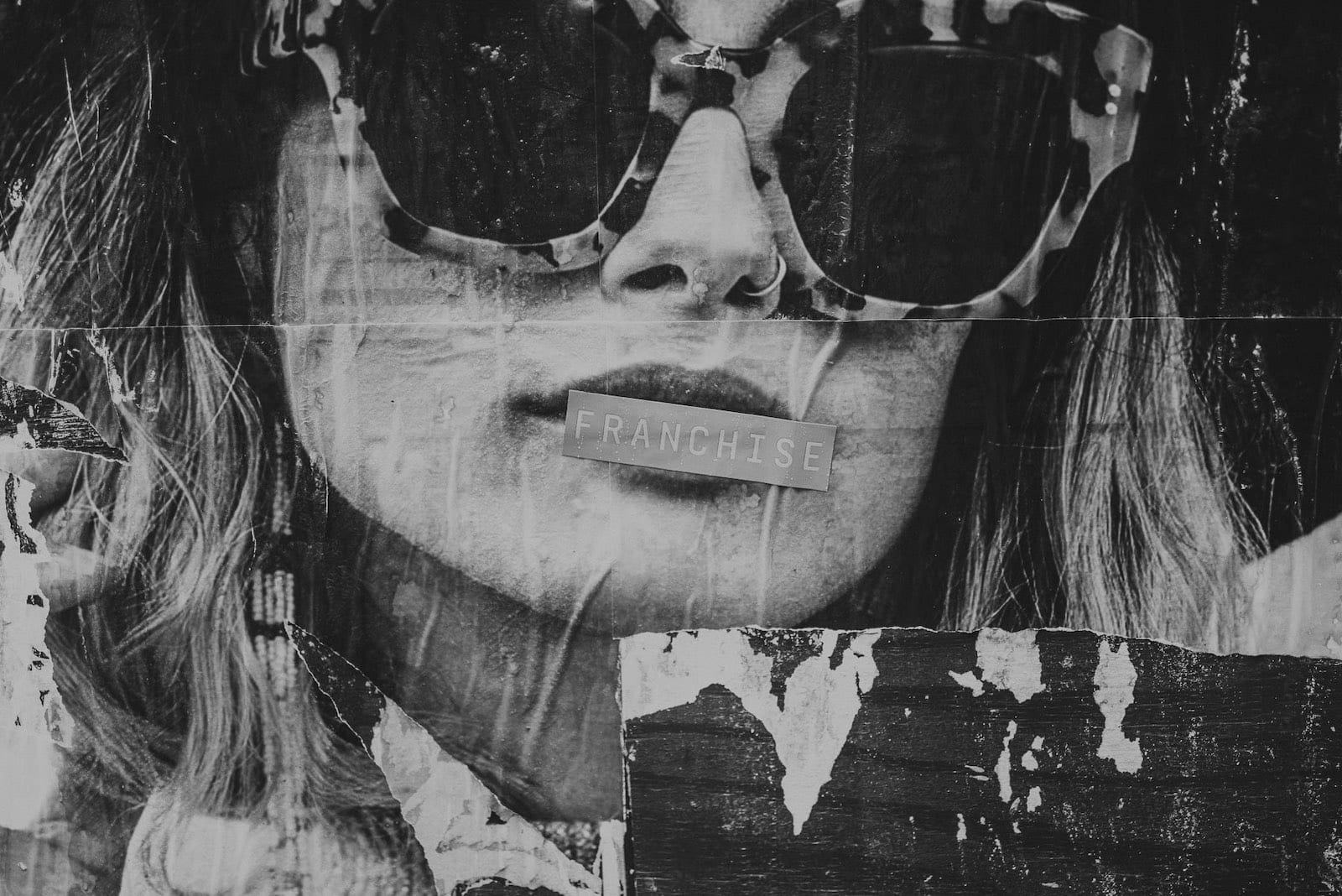 Black and white ad of woman on a wall with Franchise over lips