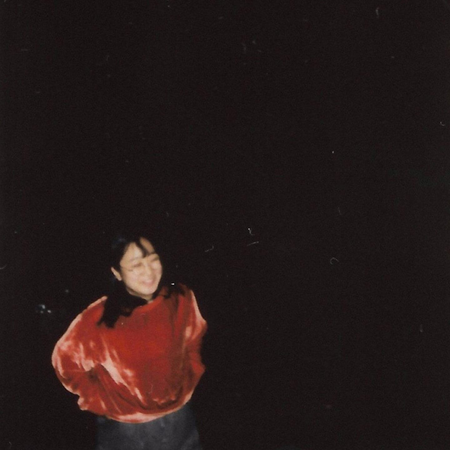 Blurry image of a woman wearing a red velvety-like sweater