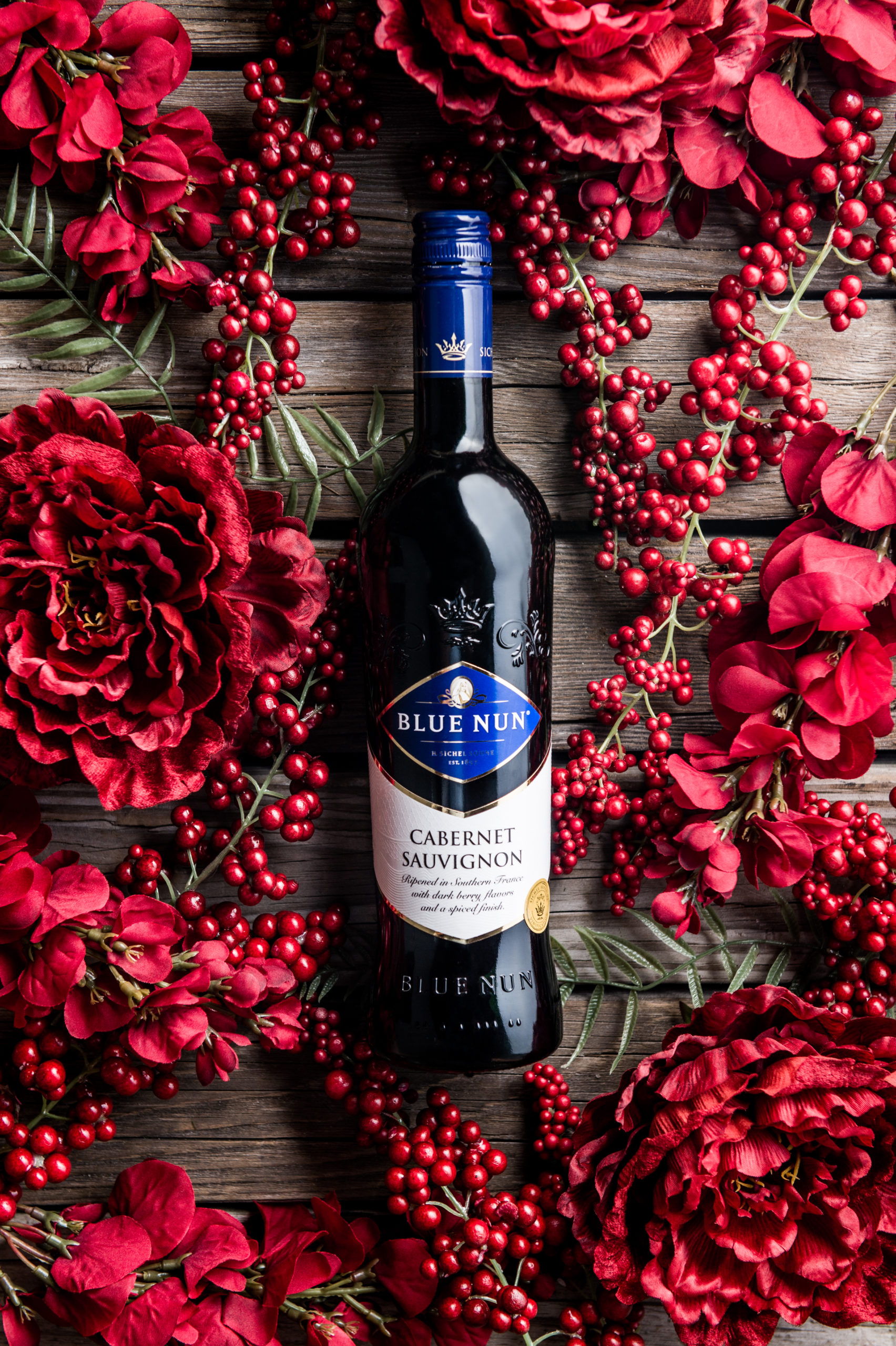 Professional Photography Services to elevate your brand C&I Studios Creative Marketing Blue Nun Cabernet Sauvignon bottle amongst red decorations