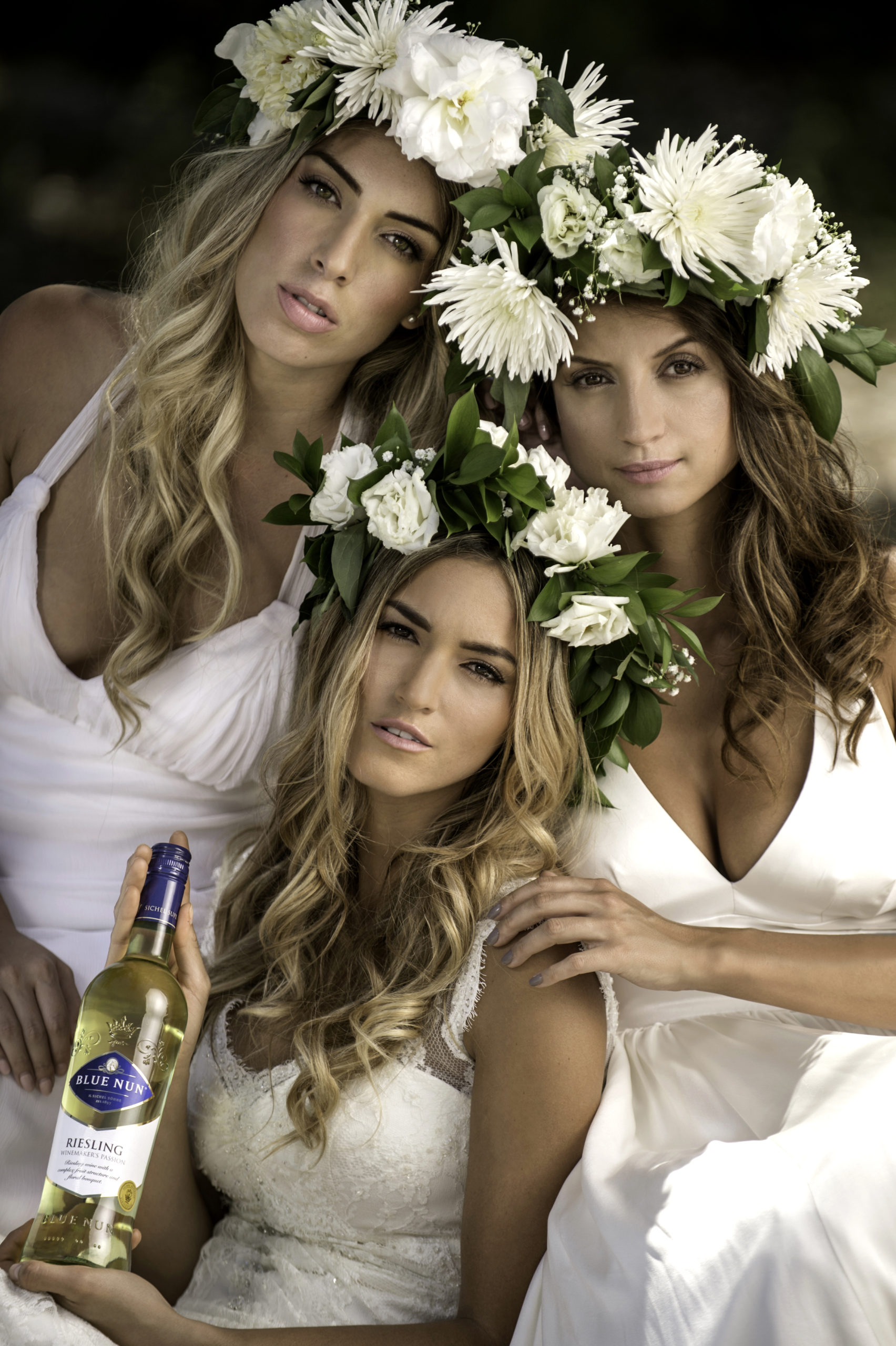 Professional Photography Services to elevate your brand C&I Studios Creative Marketing Blue Nun Three women wearing flower headdresses posing for the camera wearing white dressing gowns with one holding a bottle of Riesling wine