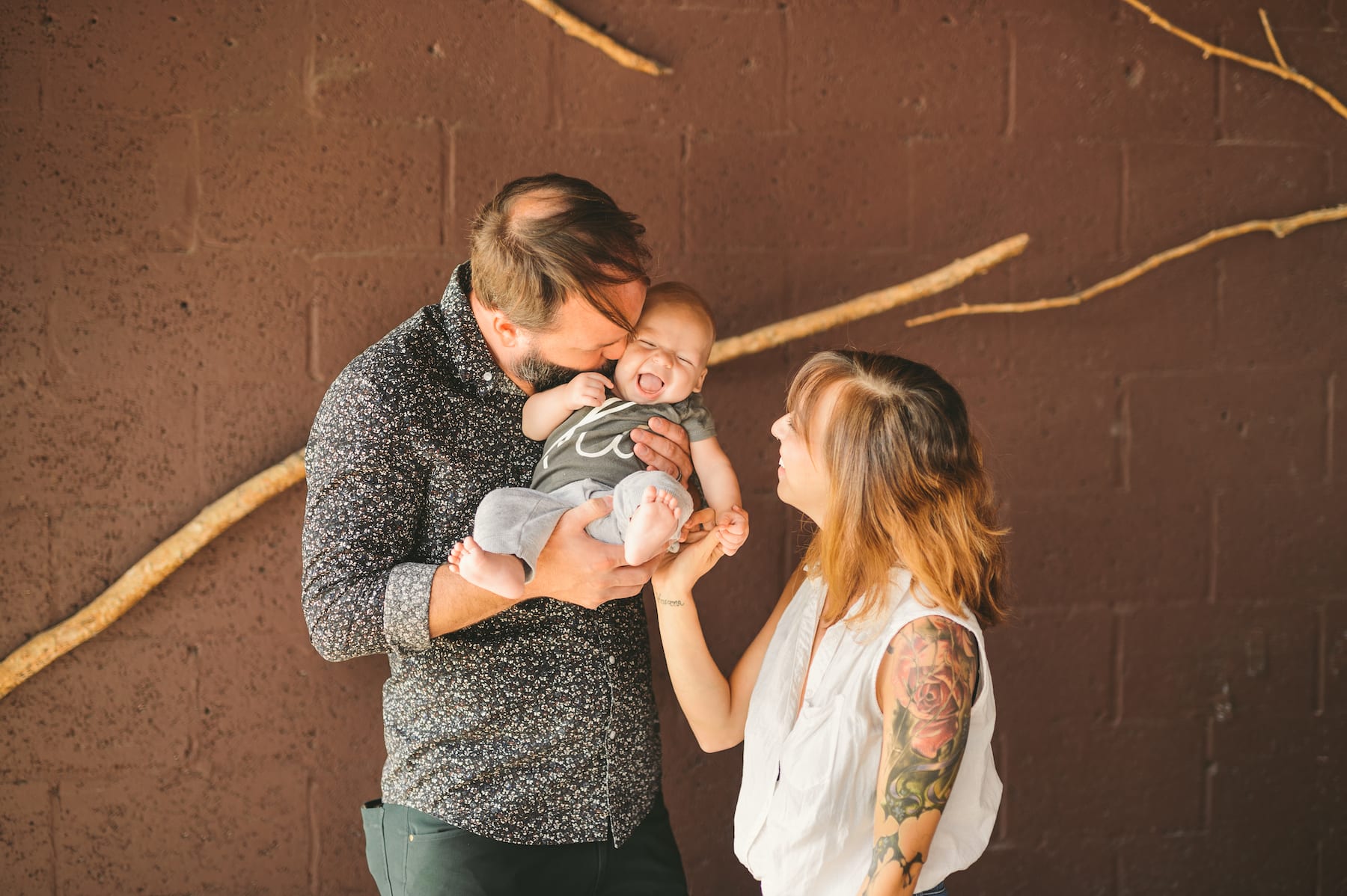 Brew Urban Cafe Man and tattooed woman with man holding and kissing a baby who is smiling all posing for the camera