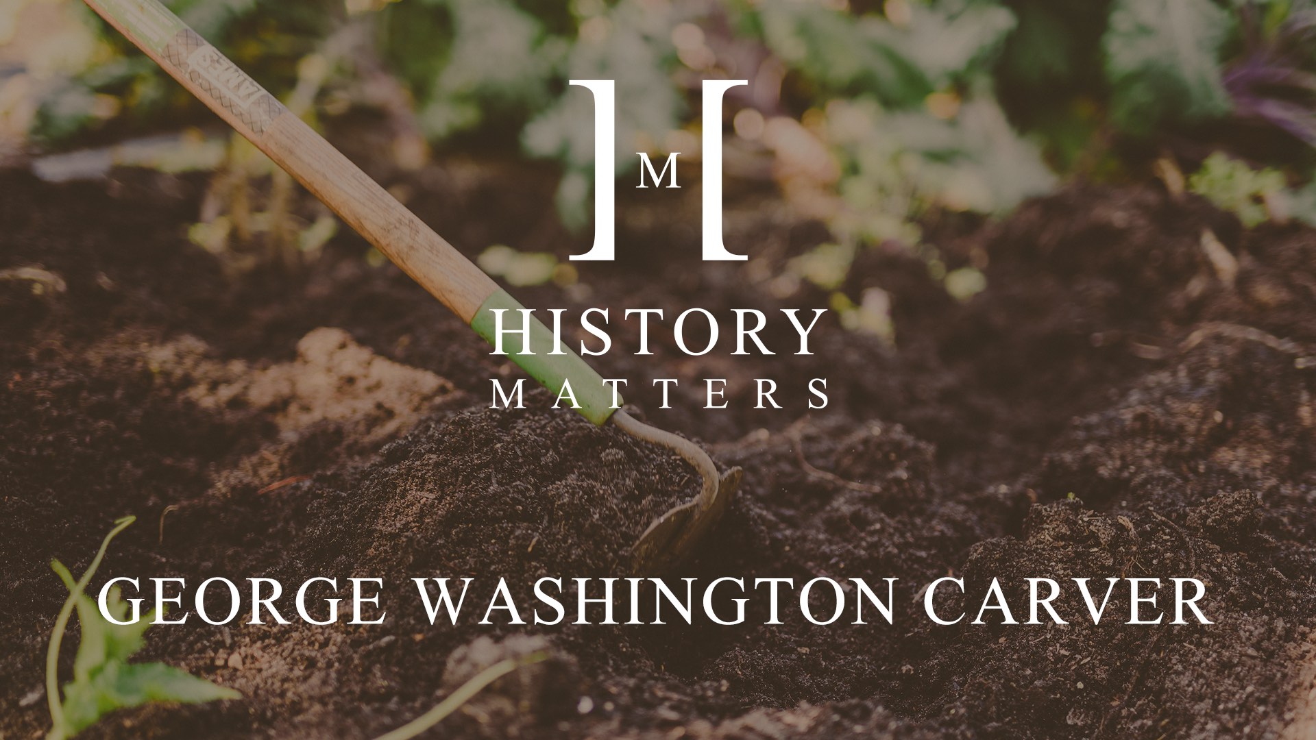 White HM George Washington Carver logo with background showing a hoe being used in dirt in a garden