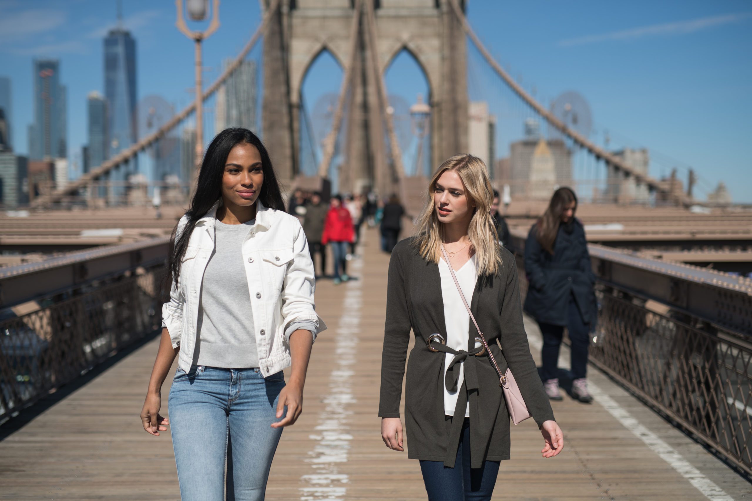 IU C&I Studios Page Professional photography services for HauteHouse Theorie and Sedu in NYC Woman with long black hair and woman with long blond hair walking on a bridge with people in the background