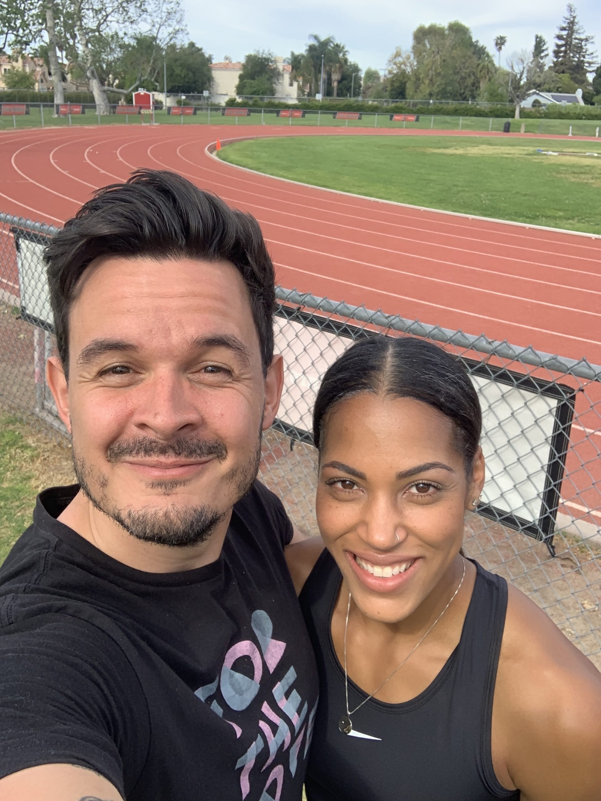 Karelle Edwards Canadian Olympic Athlete smiling and posing with a man in front of the track