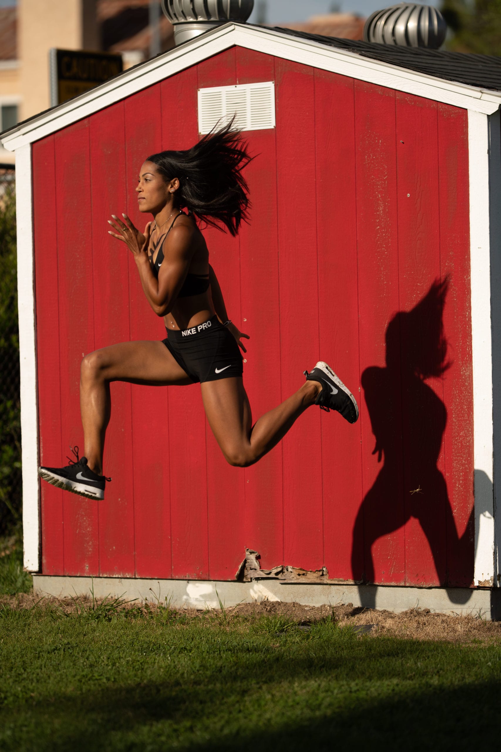 Karelle Edwards Canadian Olympic Athlete jumping in front of a red shed