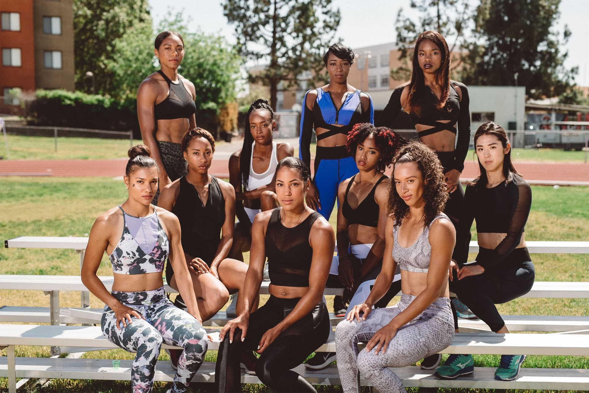 Group of track athletes posing for camera from a multilevel bench